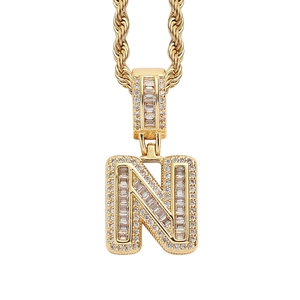 Detail view of gold-plated iced-out letter N pendant with baguette and round cubic zirconia