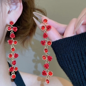 Close-up of elegant long tassel earrings with red rose and crystal drops on model
