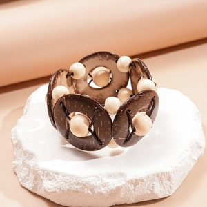 Détail de perles en bois et coque de coco bohème sur un socle en pierre blanche