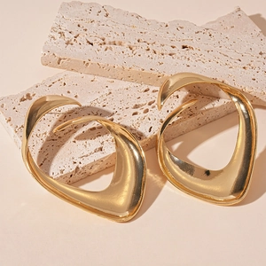 Close-up of golden irregular twisted geometric metal studs on textured stone stand