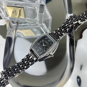 Detail of tonneau-shaped black emerald quartz watch with rhinestone bezel on reflective metal