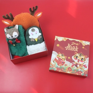 Close-up of winter gift box with knitted reindeer hat and festive cartoon gloves