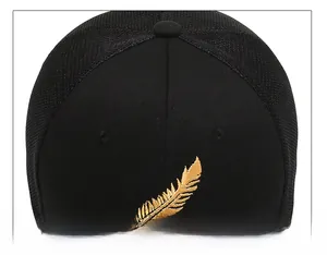 Close-up of black baseball cap top featuring golden feather embroidery and mesh details