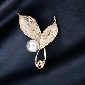 Golden leaf brooch with pave zircons, white pearl and clear gemstone on blue silk
