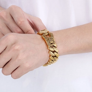 Detail of gold Cuban chain bracelet featuring an engraved tiger head clasp on model