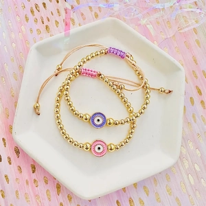 Bohemian evil eye beaded bracelets in pink and purple with adjustable golden bead strands
