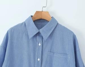 Detail eines blau-weiß gestreiften Hemdes mit klassischem Kragen, Knöpfen und Tasche