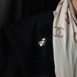Detail of Christmas snowman brooch with gold finish, pearls, and red gems on a scarf