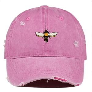 Close-up of pink bee embroidery and distressed rip details on washed vintage baseball cap