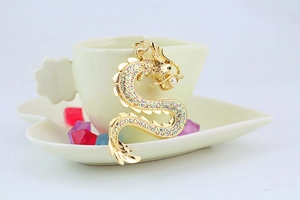 Détail d'un porte-clés dragon doré orné de strass colorés et d'une perle délicate