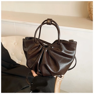 Detailed view of the dark brown ruched cloud bag featuring glossy leather and ring handles