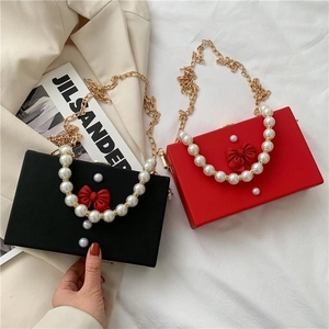 Elegant box bag with pearl handle, ribbon bow, and gold chain strap in red and black