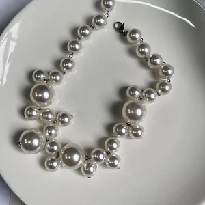 Detail of bohemian pearl necklace featuring mixed size white pearls on ceramic tray