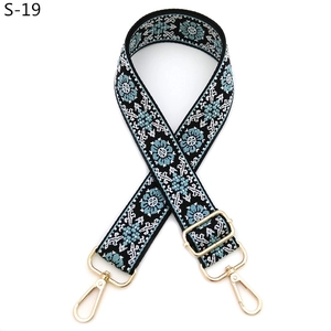 Close-up of ethnic style embroidered bag strap with blue floral patterns and gold hooks