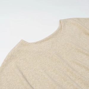 Detail of oat-colored knitted top showing soft fabric texture and neckline stitching