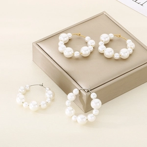 U-shaped stainless steel hoop earrings with graduated pearls in gold and silver finishes