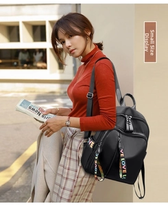 Small black nylon backpack with colorful LOVE letter straps worn in a street setting