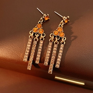 Detail of vintage gold-tone tassel earrings with amber crystals on brown leather