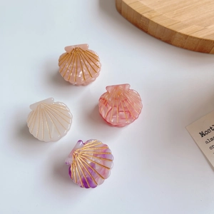 Set of four shell-shaped hair clips in pink and white marble on a white background