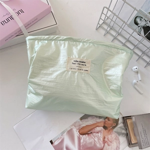 Detail view of light green nylon drawstring makeup bag with brand label and satin finish