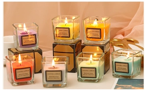 Close-up of assorted colorful scented candles in square glass jars with natural plant extracts
