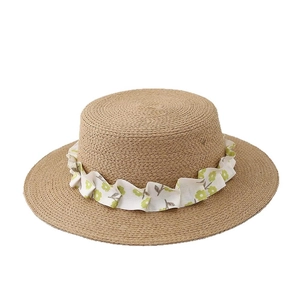 Flat top straw sun hat with white floral ribbon decoration for beach and summer wear