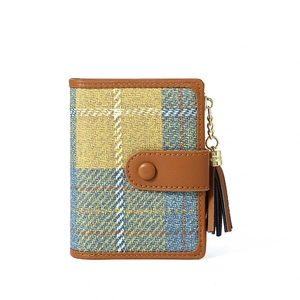 Detail of blue and yellow plaid coin purse with brown leather trim and golden tassel