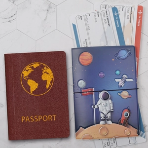 Detailed view of dark red and navy passport holders with gold map and space patterns