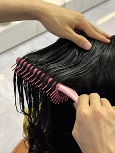 Close-up of pink vent brush detangling wet hair with ergonomic handle design