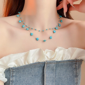Detail of bohemian gold plated double layer necklace with turquoise heart beads
