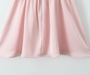 Gros plan détaillé de l'ourlet de robe en satin rose avec plis et coutures soignés