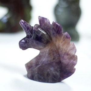 Macro shot of hand-carved natural purple amethyst crystal unicorn head sculpture