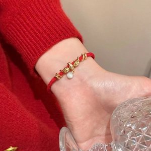 Détail du bracelet tressé rouge avec breloque nuage dorée et perle blanche au poignet