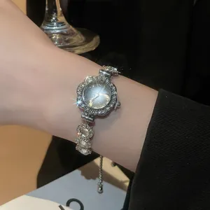 Close-up of floral crystal bezel and silver link bracelet on woman's wrist