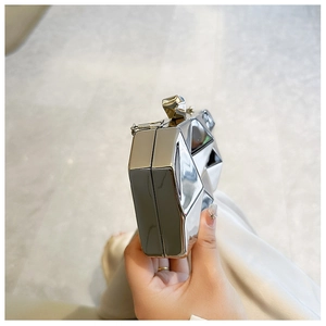 Close-up of silver geometric clutch with mirror finish showing side depth and clasp