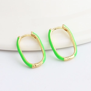 Close-up of golden oval hoop earrings with vibrant green enamel and hinged closures