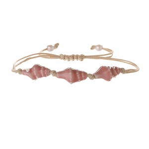 Macro view of pink conch beads and beige woven cord on this adjustable ocean bracelet