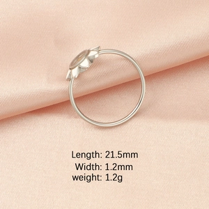 Macro detail of silver floral ring with size dimensions on pink satin background