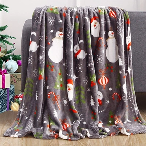 Detail of Christmas flannel blanket with snowman and tree print on a cozy sofa