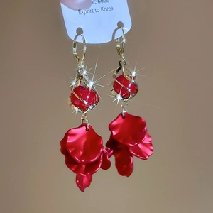 Detailed view of red metal petal tassel earrings with gold spiral bead accents