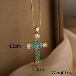 Macro shot of gold cross pendant with turquoise stones and zircons detailing dimensions