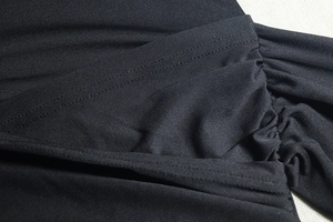 Detailed close-up of the black ruched fabric and reinforced stitching on the bodycon dress