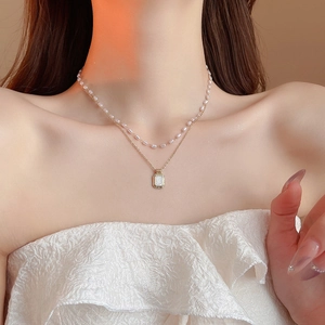 Close-up of double-layer vintage necklace with rice pearls and gold rectangle pendant