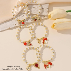 Detail of beaded bracelet set with cherry and heart charms on warm silk background