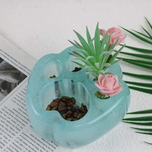 Detalle de molde de resina con forma de pata de gato para macetas con purpurina y plantas