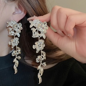 Elegant silver tassel earrings with flower and leaf design worn by a model