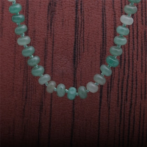 Detailed close-up of natural green aventurine oval beads on a rustic wooden background