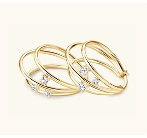 Macro shot of gold spiral hoop earrings featuring triple band design and white zircons