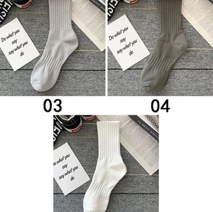 Detail of ribbed cuffs and arch support on cotton crew socks in white and grey tones