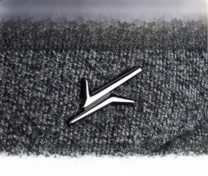 Macro detail of winter baseball cap grey tweed fabric with silver metal logo emblem